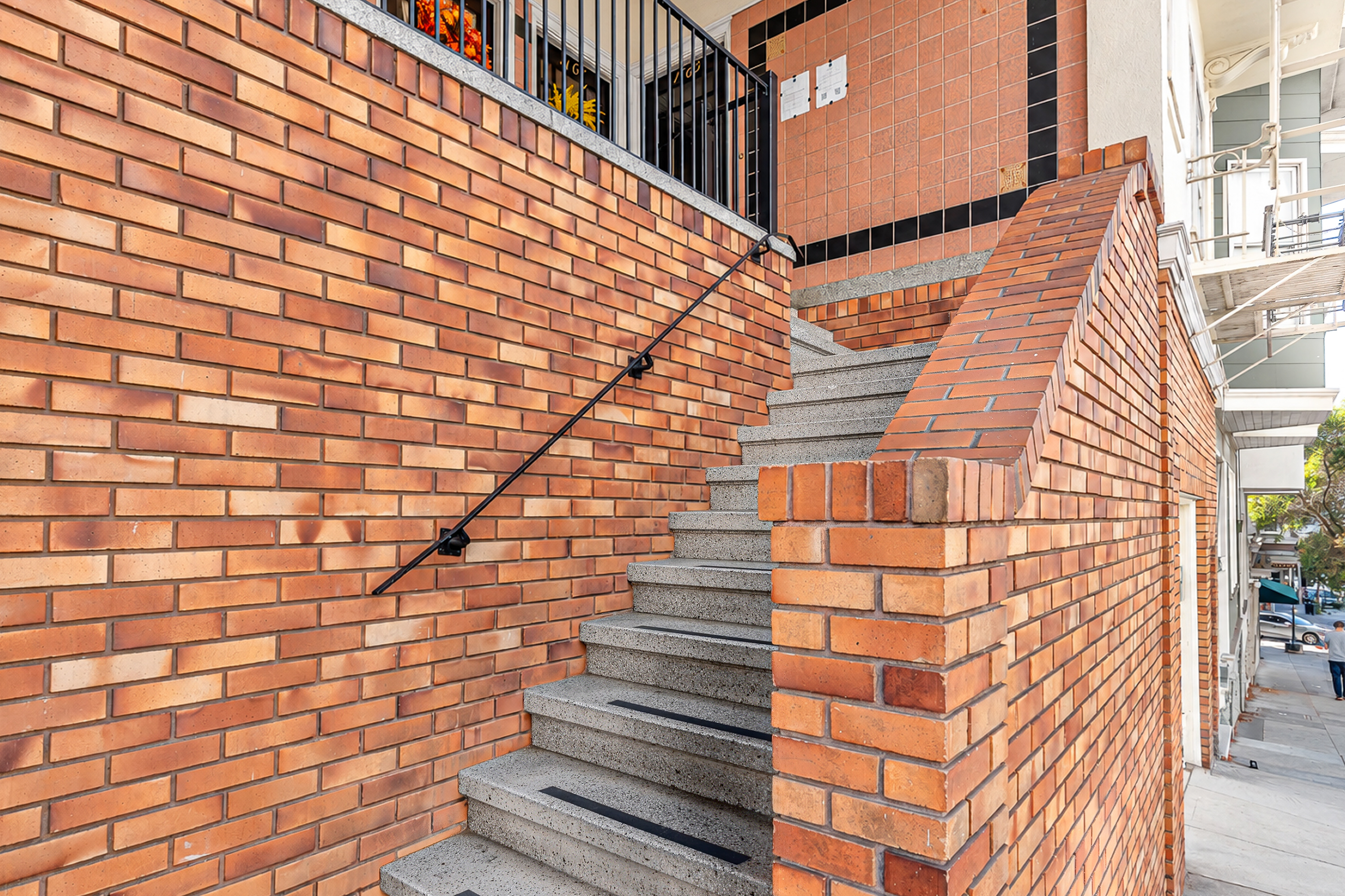 A staircase with a black railing leads up to a balcony.
